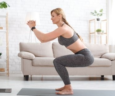 Woman With Fitness Tracker Crouches And Watches At